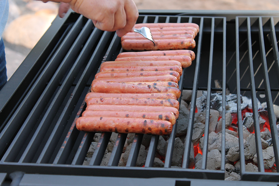 Person som grillar korvar på en grill