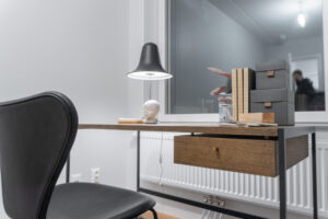 Ett skrivbord, en stol och en lampa står i ett rum