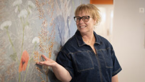 Bodil Pettersson, kostnär, framför väggkonst.