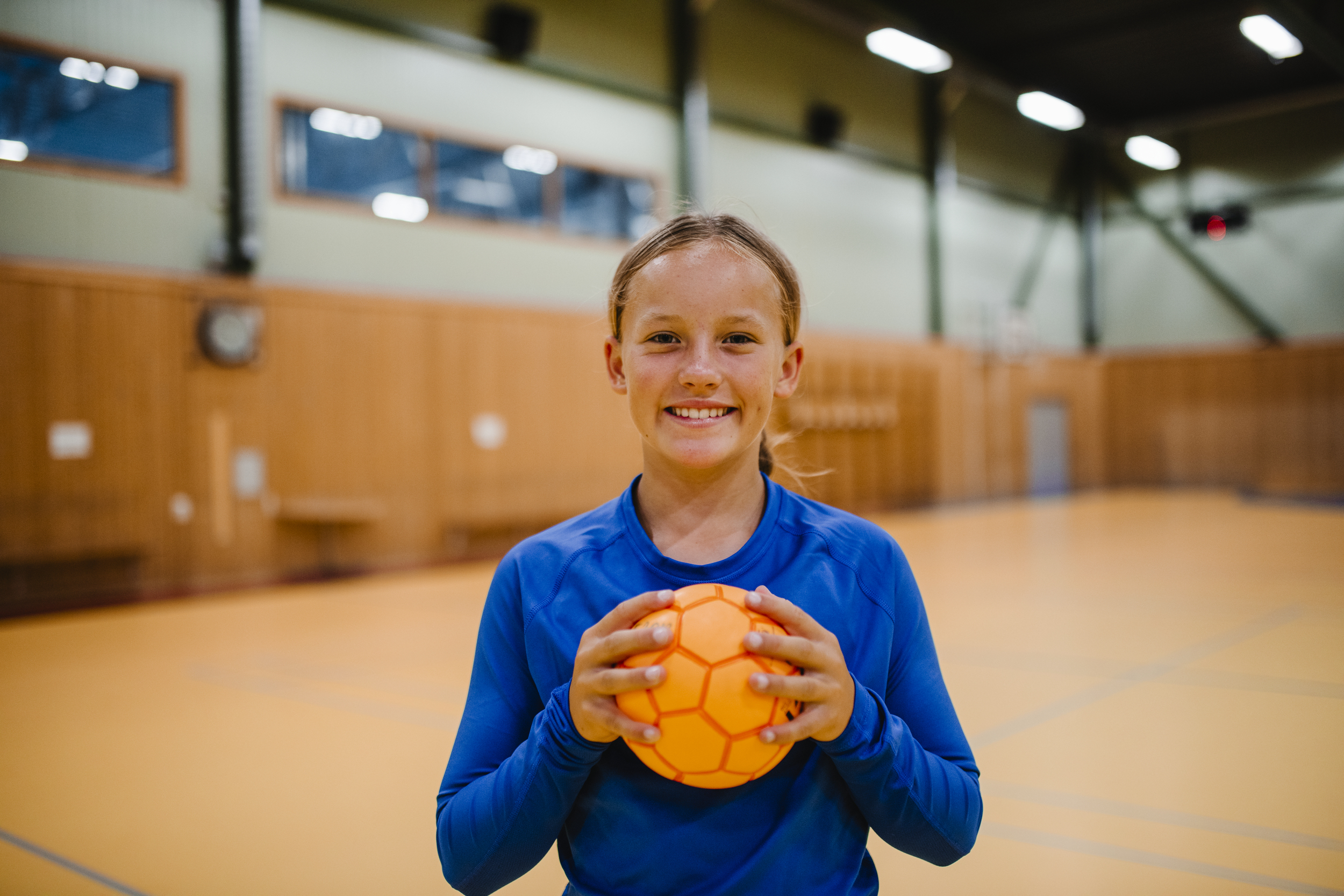 Tjej som ler och håller i en handboll.